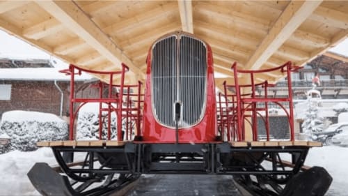 Wagon de train rouge vintage à Chez Francine à Flumet enneigé, France, avec architecture bois au-dessus