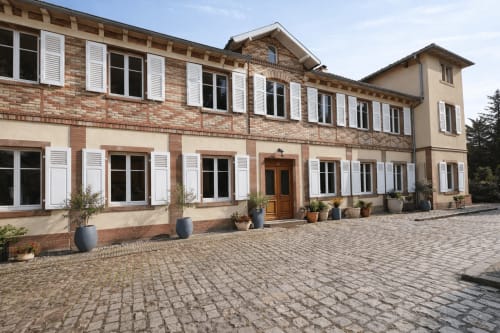 Cour de la Villa Avril & Spa à Sélestat avec façade en brique, volets blancs et plantes en pots