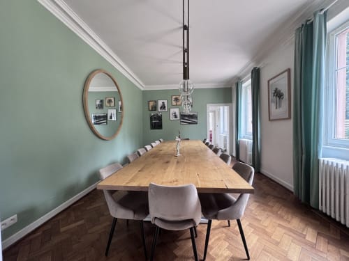 Salle à manger élégante à la Villa Avril & Spa à Sélestat avec murs vert sauge, table en bois et mobilier contemporain