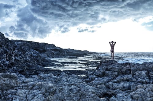 Silhouette d'une personne debout sur les falaises rocheuses de la côte, surplombant l'océan près de Bédoin, France