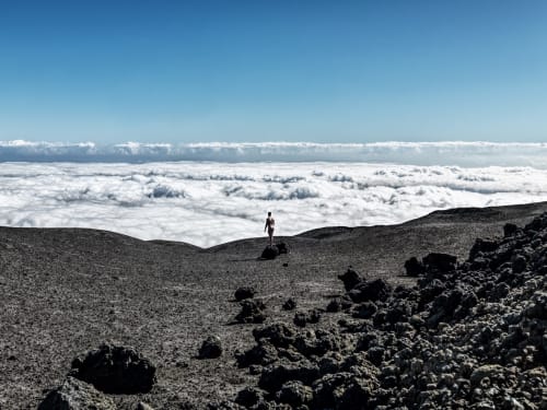 Randonneur debout sur un terrain volcanique au-dessus d'une couche de nuages près de Bédon, France