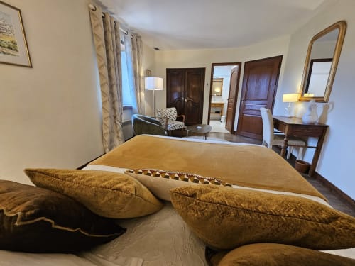 Luxurious bedroom at Château de Ribourdin with gold pillows, sitting area, and garden views in Chevannes