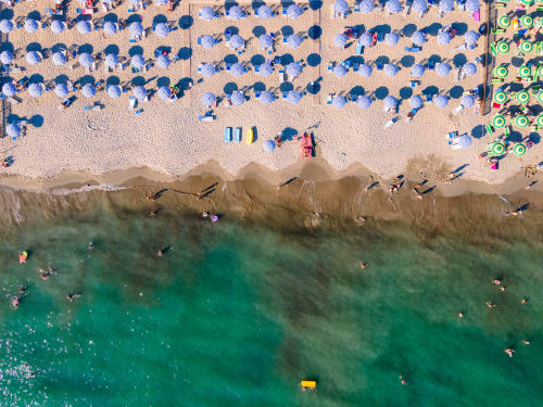 Vista aerea di La Casetta dei Ronchi con ombrelloni blu, bagnanti e acque turchesi del Mediterraneo in Italia