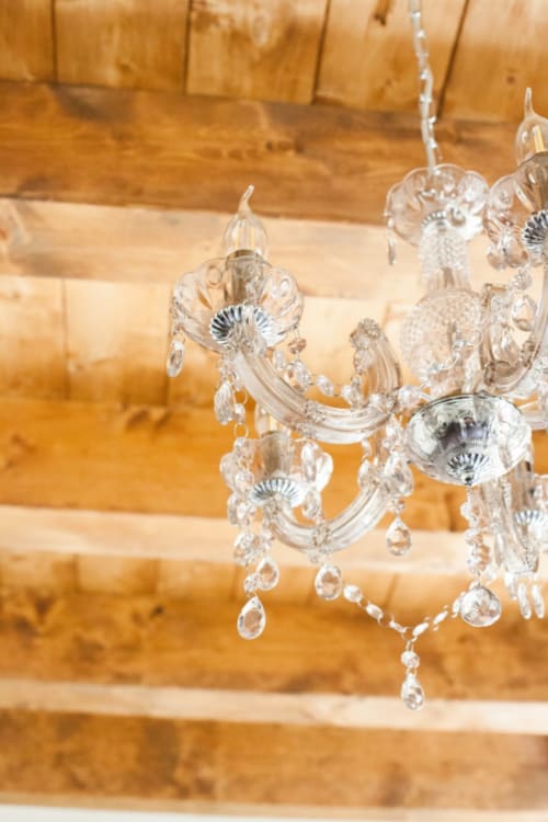 Crystal chandelier with teardrop pendants against wooden beam backdrop at Alessia's Place, Como