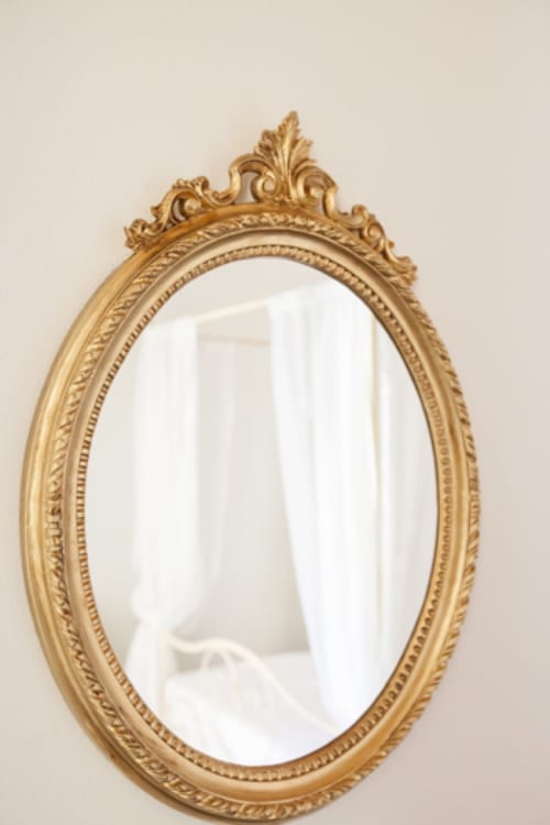 Ornate gold oval mirror with decorative carved frame at Alessia's Place bed and breakfast in Como