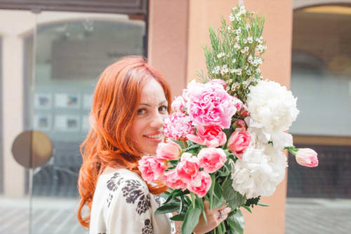 Donna con capelli rossi che tiene fiori rosa e bianchi presso la struttura ricettiva Alessia's Place a Como, Italia