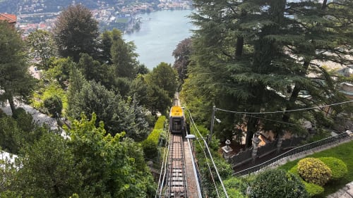 Funicular railway descending through lush trees toward Lake Como, near Alessia's Place in Como, Italy