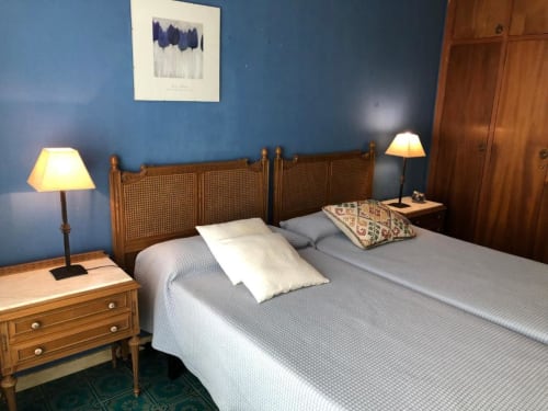 Habitación del hotel Casa María con camas gemelas, cabecero de ratán, paredes azules y lámparas de noche cálidas en Artana, España