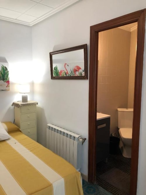 Habitación con detalles en amarillo en el hotel Casa María de Artana, España, con cama, cómoda con lámpara, radiador y puerta abierta