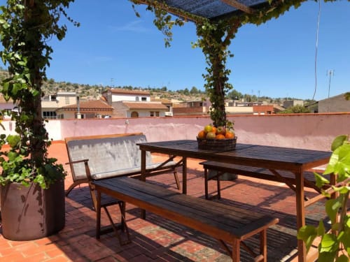 Terraza de la villa Casa María en Artana con mesa de comedor, vistas a las montañas y pérgola cubierta de hiedra
