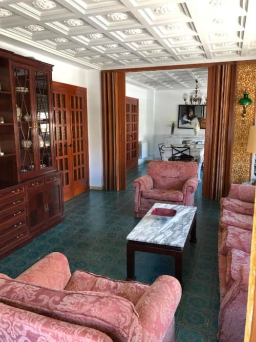 Elegante sala de estar de la villa Casa María en Artana con asientos tapizados en rosa, mesa de café de mármol y techo decorado