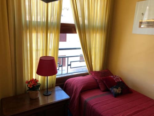 Pequeña habitación doble en Casa María de Artana con ropa de cama burdeos, cortinas amarillas, vistas a las montañas desde la terraza y mesita de noche