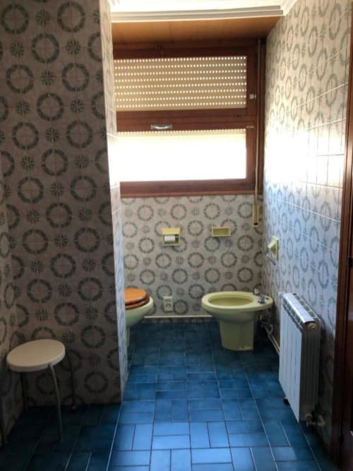 Baño compartido del hotel Casa María en Artana con dos inodoros, bidé, papel pintado estampado y piso de azulejos azules