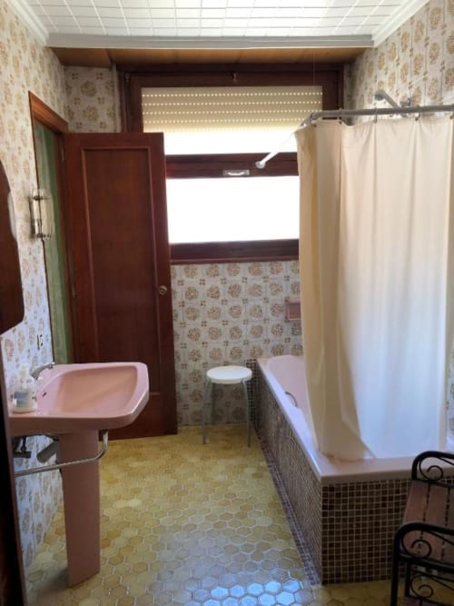 Baño del hotel Casa María en Artana con lavamanos rosado, bañera blanca, inodoro y cortina de ducha color crema