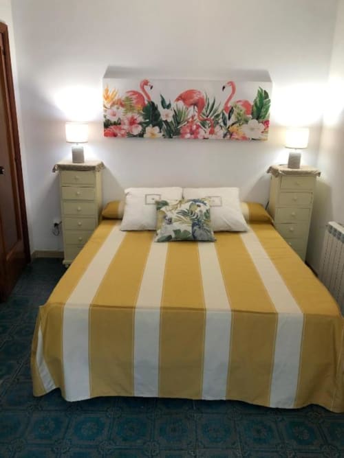 Luminosa habitación doble en hotel Casa María con ropa de cama de rayas amarillas, almohadas crema, arte floral con flamencos y decoración coordinada