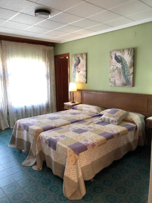 Luminosa habitación doble en hotel Casa María con dos camas, paredes verdes, arte de pavo real y vistas a la montaña en Artana, España.
