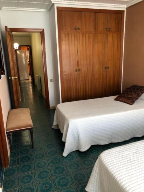 Habitación doble con colchas acolchadas blancas, armarios de madera y piso de azulejos tradicionales en Casa María, Artana.