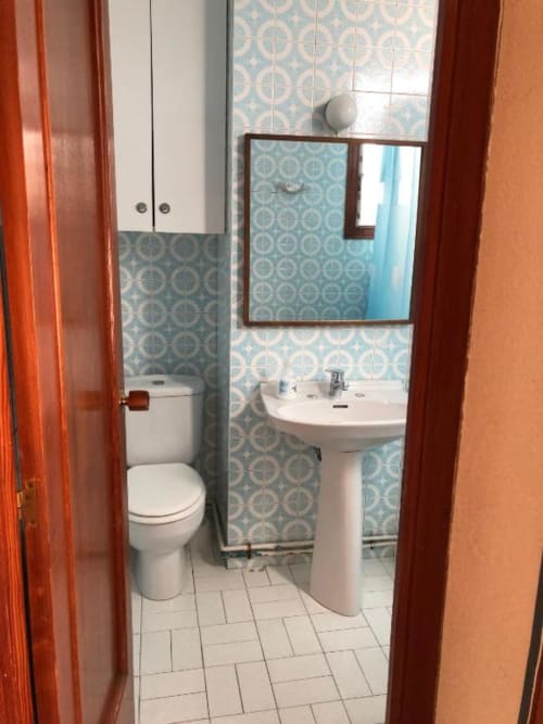 Baño moderno del hotel Casa María en Artana con lavabo de pedestal blanco, inodoro, paredes alicatadas y espejo enmarcado