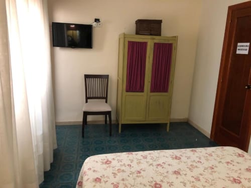 Habitación doble de Casa María hotel en Artana con cama, silla negra, armario amarillo, TV montada en pared y piso de azulejos