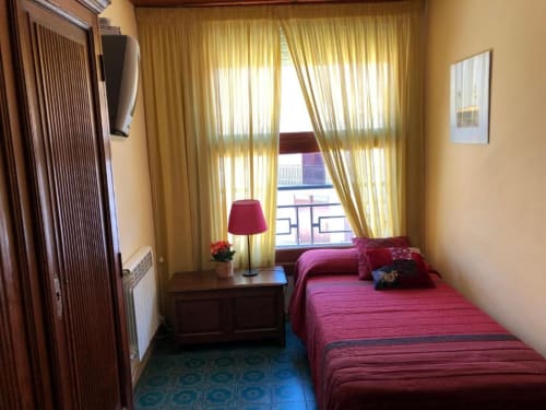 Habitación doble pequeña en Casa María de Artana con vistas a la montaña, cama burdeos, muebles de madera y cortinas amarillas