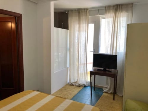 Amplia habitación doble en el hotel Casa María de Artana con TV, ropa de cama a rayas, acceso a terraza y vistas a las montañas