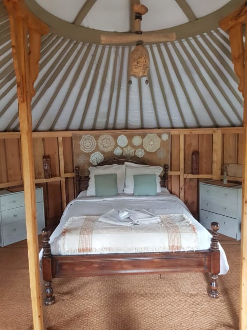 Chambre cosy dans une yourte à La Toile Sous Les Etoiles avec lit en bois, draps blancs et napperons à Charron