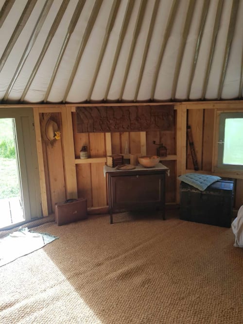 Chambre spacieuse de yourte à La Toile Sous Les Etoiles, Charron, avec étagères en bois, meubles d'époque et vue sur le jardin