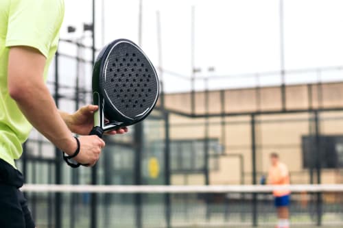 Racchetta da padel tenuta presso la struttura tennistica La Casetta dei Ronchi in Italia con campo e giocatore sullo sfondo