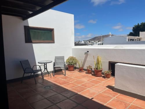 Sunny rooftop terrace at Villa Estrella Polar in Tahiche with mountain views, potted plants, and outdoor seating area
