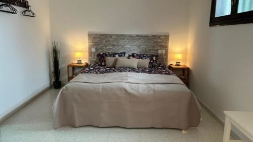 Modern bedroom at Villa Estrella Polar in Tahiche with stone headboard, twin lamps, and mountain views