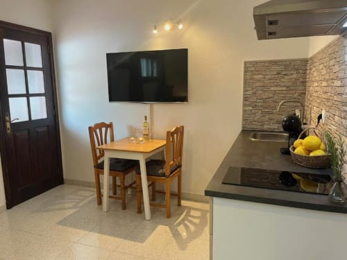 Modern apartment kitchen and dining area at Villa Estrella Polar, Tahiche, with flat-screen TV, dining table, and equipped