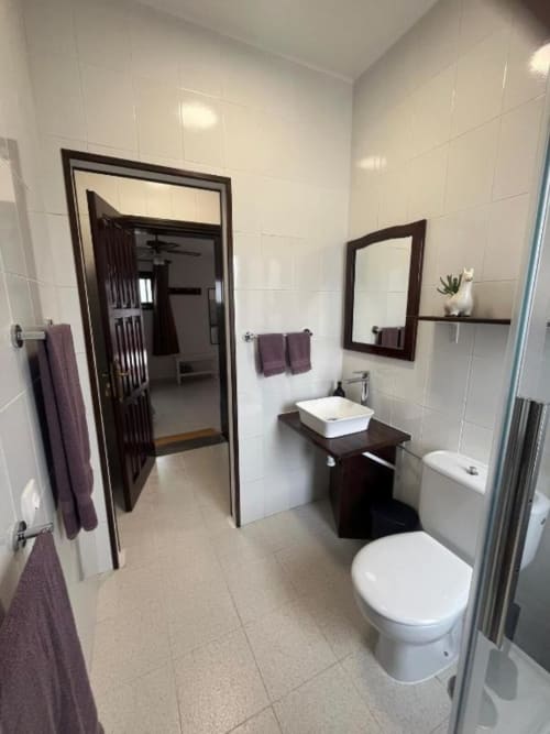 Modern bathroom in Villa Estrella Polar apartment, Tahiche, featuring white tile walls, dark wood vanity with white sink,