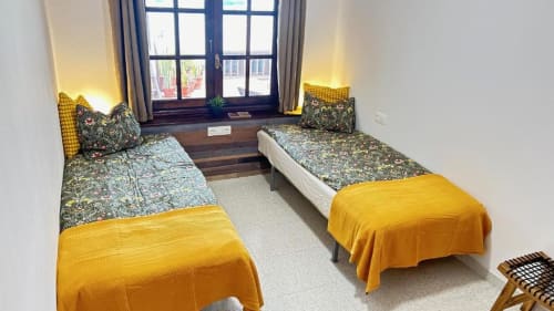 Quadruple room at Villa Estrella Polar with two twin beds, yellow throws, patterned bedding, mountain views through French