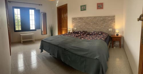 Spacious double bedroom at Villa Estrella Polar with stone accent wall, garden views, and modern amenities in Tahiche