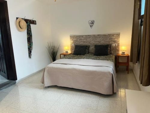 Modern bedroom at Villa Estrella Polar with stone headboard, beige bedding, nightstands with lamps, and mountain view access