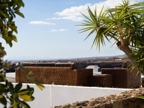 Villa Estrella Polar rooftop lounge with wicker seating and palm trees overlooking Tahiche countryside