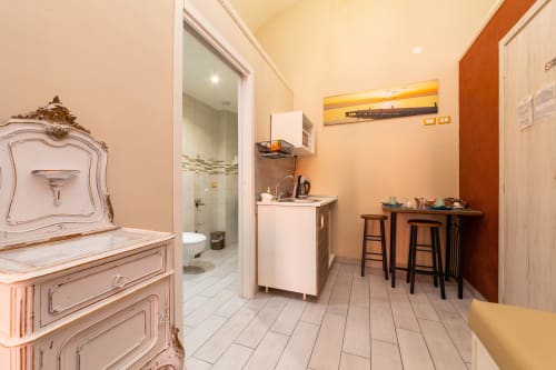 Spacious room at Casa Scola Loano BnB in Italy with kitchenette, bathroom, and vintage pink furnishings