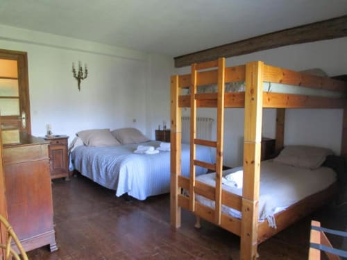 Spacious quadruple room at Domaine de Cabrières with wooden bunk beds and single bed, parquet flooring, exposed beams, and