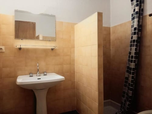 Bathroom at Domaine de Cabrières B&B in St Jean Du Gard with pedestal sink, mirror, and beige tile walls