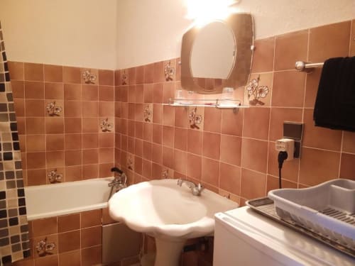 Bathroom with terrace access at Domaine de Cabrières, featuring terracotta tiled walls, pedestal sink, and bathtub in Family