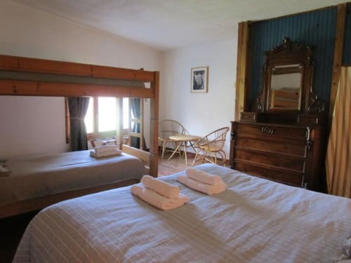 Spacious quadruple room at Domaine de Cabrières with four-poster bed, wooden furniture, and lounge area in St Jean Du Gard