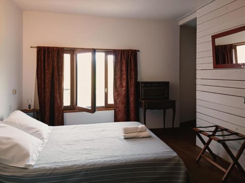 Spacious double bedroom at Domaine de Cabrières with queen bed, burgundy curtains, wooden furniture, and shiplap walls in St