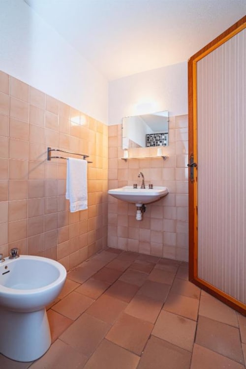 Modern bathroom at Domaine de Cabrières in St Jean Du Gard with terracotta tiles, wall-mounted sink, toilet, and bidet