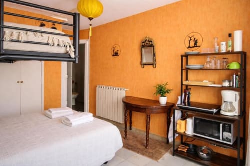 Bright family room at Domaine de Cabrières with orange walls, loft bed, kitchenette, wooden desk, and shelving in St Jean Du