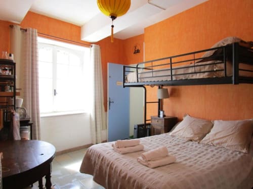 Bright family room with orange walls, loft bed, and garden view at Domaine de Cabrières in St Jean Du Gard