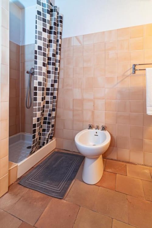 Modern bathroom in Domaine de Cabrières with peach tile walls, walk-in shower with mosaic accent, and pedestal sink in St