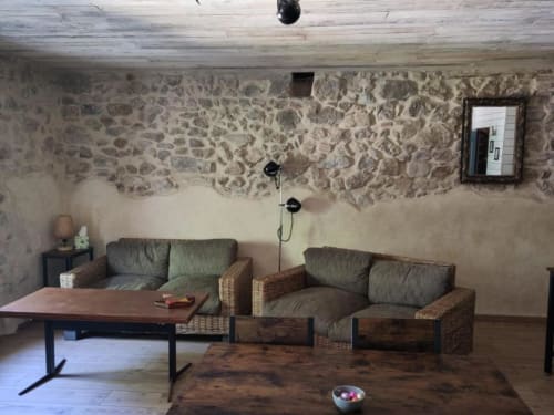 Stone walls and rustic furnishings in a cozy lounge area at Domaine de Cabrières B&B in St Jean Du Gard, France.