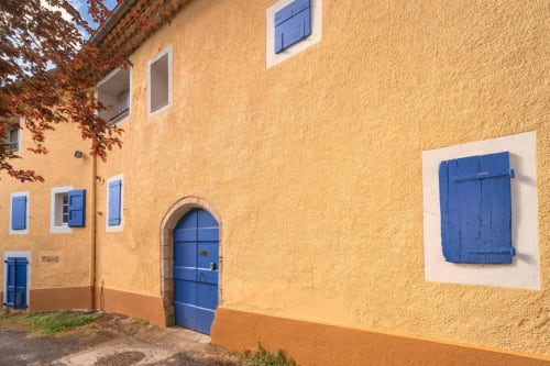 Charming yellow stone facade of Domaine de Cabrières B&B in St Jean Du Gard with blue shutters and arched door