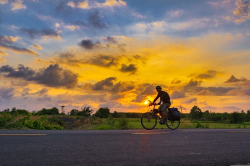 Cyclist riding at sunset near Le Prieuré Notre-Dame in Montfrin, France