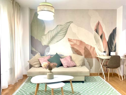 Moderno apartamento estudio en Málaga Centro con sofá crema, mural botánico, alfombra geométrica y escritorio de trabajo